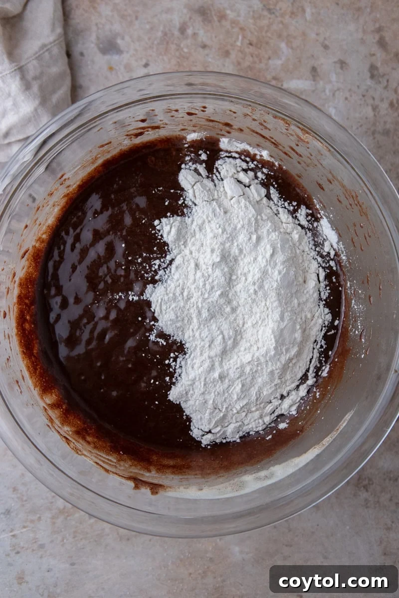 Brownie batter with flour and cornstarch sifted on top before folding
