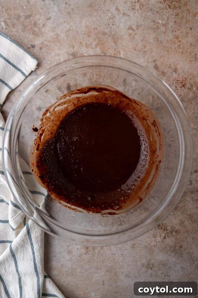 Dutch-process cocoa powder being bloomed in hot coffee to create a smooth, rich chocolate paste in a glass bowl, ready for mixing
