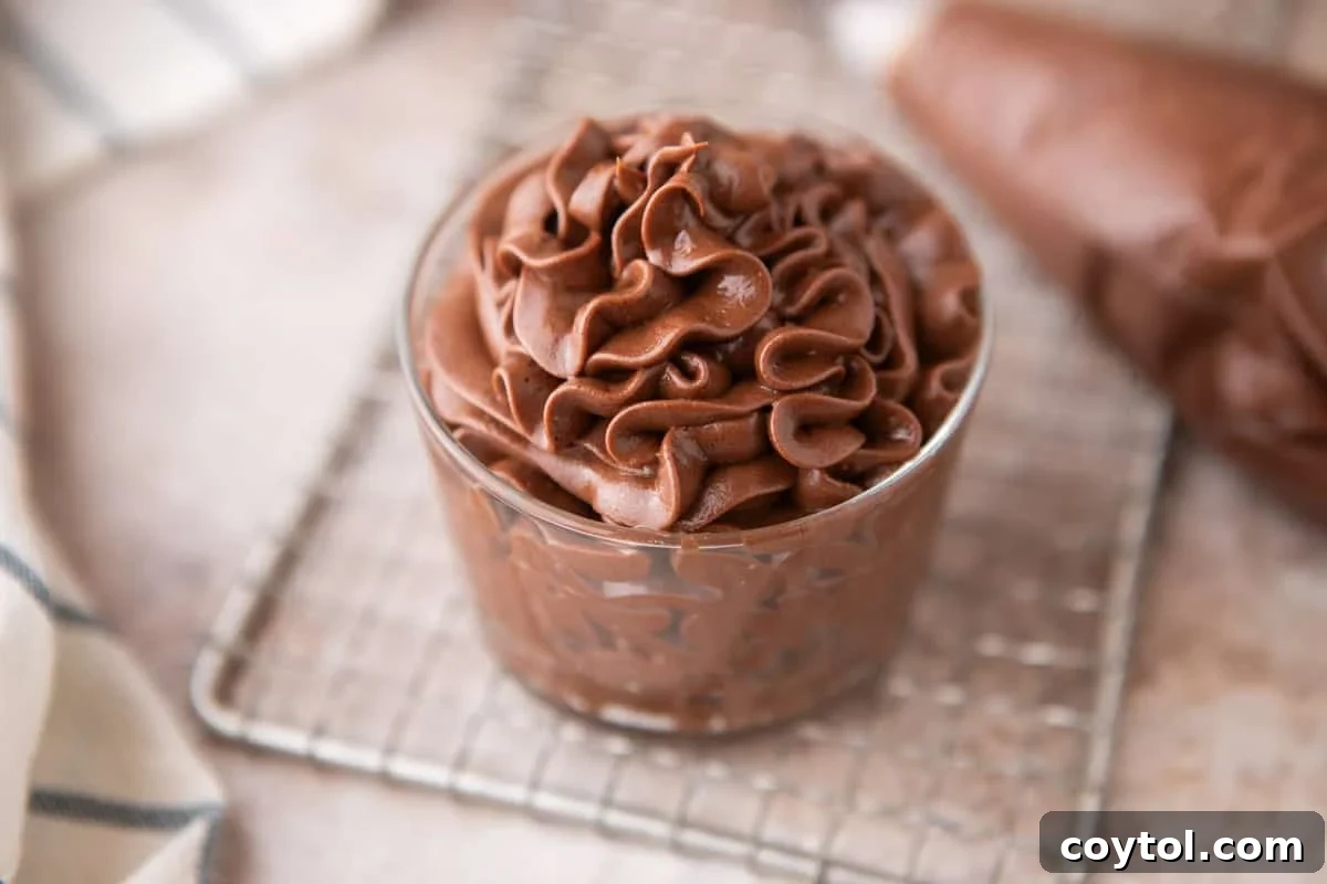 Chocolate cream cheese frosting piped into a small glass jar on a wire cooling rack