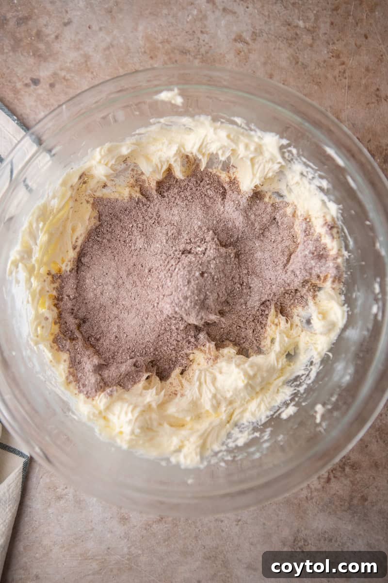 Sifted cocoa powder and powdered sugar added to beaten cream cheese and butter in a glass bowl