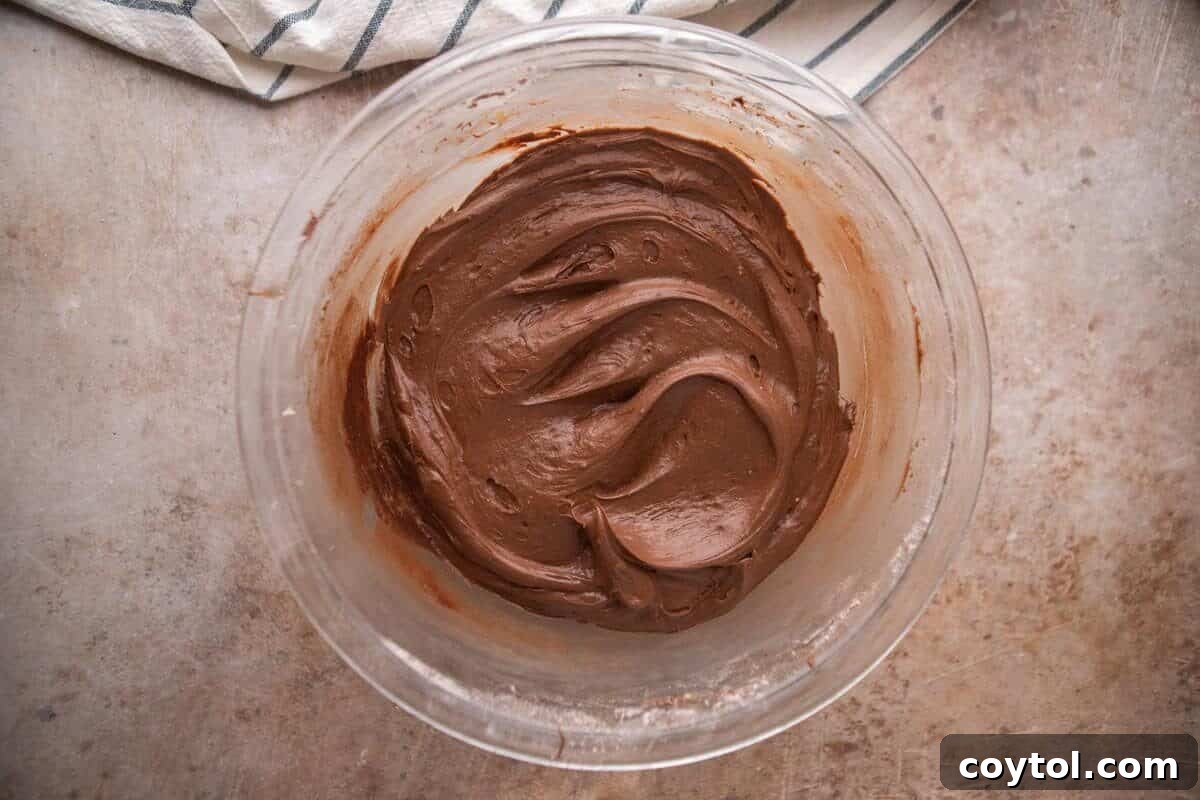 Smooth and creamy chocolate cream cheese frosting in a glass mixing bowl
