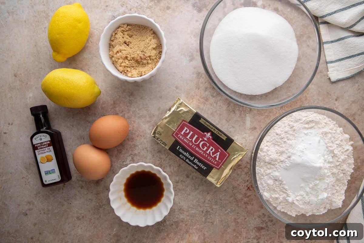 Overhead flatlay of lemon sandwich cookie ingredients including Plugrà butter, lemons, eggs, sugar, flour, and lemon extract.