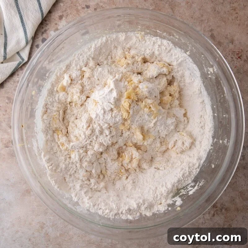 Dry ingredients added to lemon cookie dough in a glass bowl before mixing