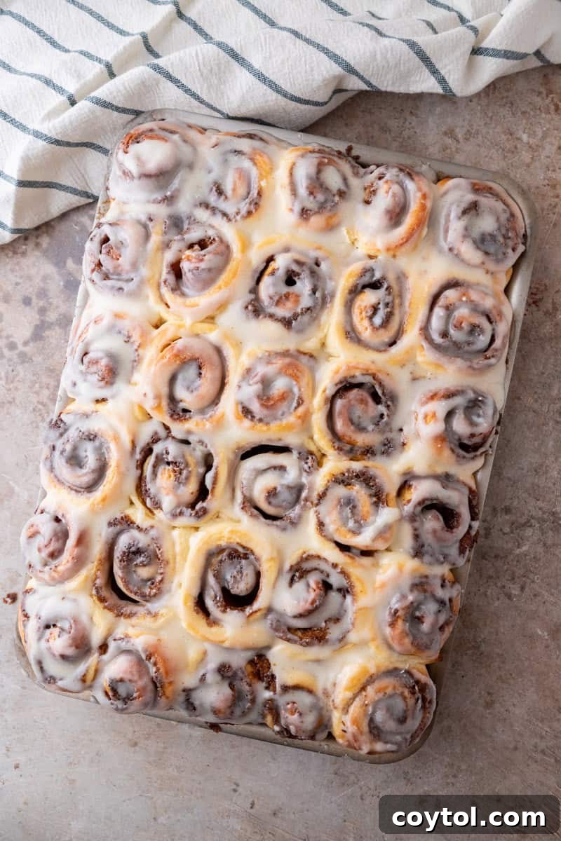 The baked mini cinnamon rolls in the sheet pan are generously drizzled with a thin, shiny cream cheese glaze.