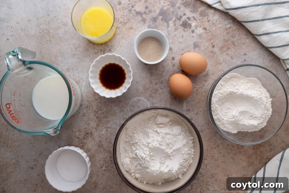 A collection of ingredients for the mini cinnamon roll dough, including all-purpose flour, bread flour, whole milk, melted butter, eggs, active dry yeast, vanilla, and sugar.