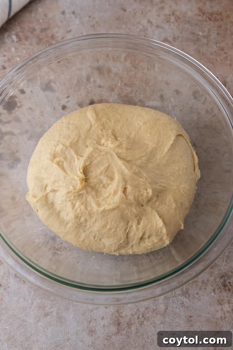 The smooth, enriched brioche-style cinnamon roll dough rests in a glass bowl after being perfectly kneaded.