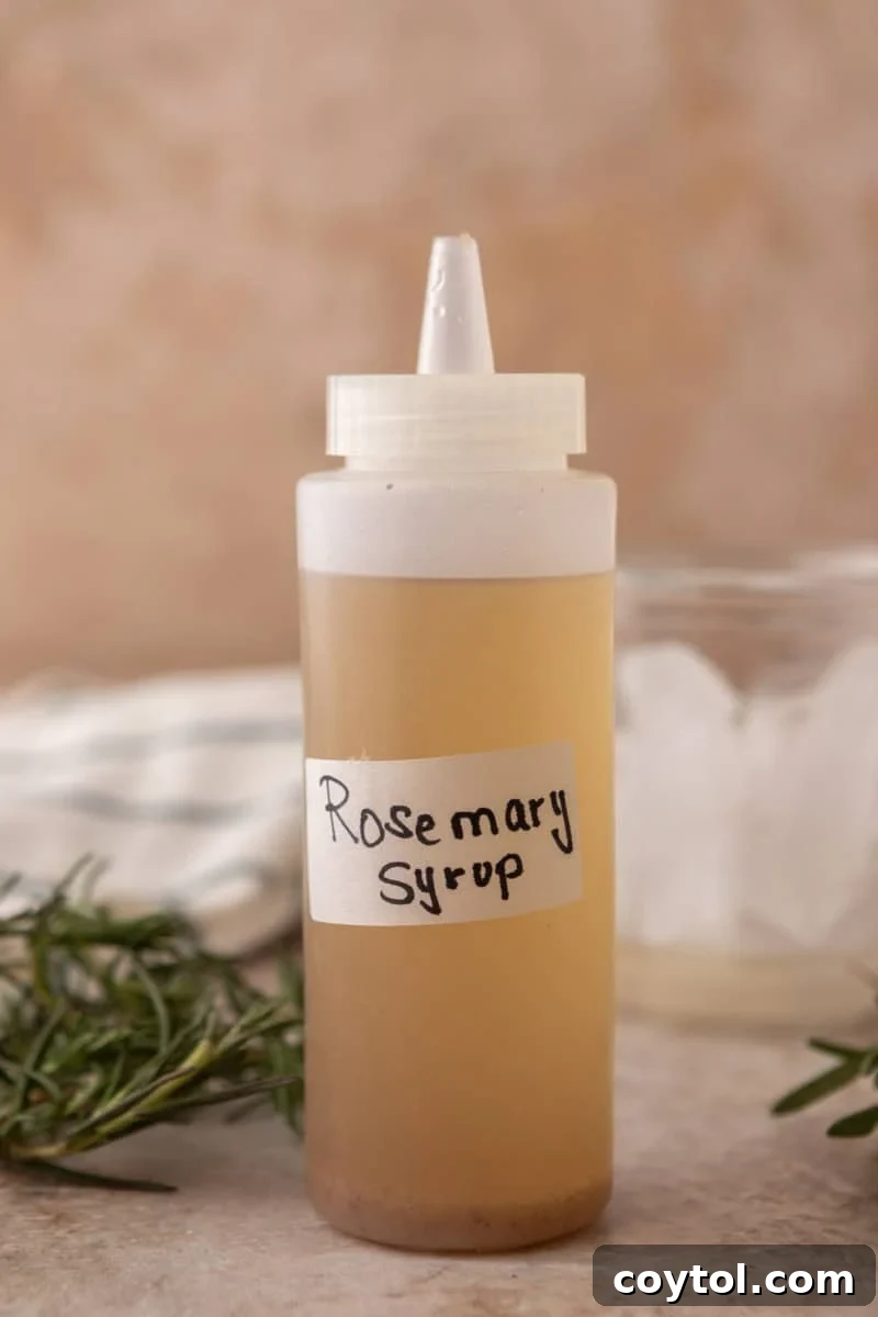 A clear squeeze bottle filled with homemade rosemary syrup, featuring a simple handwritten label.