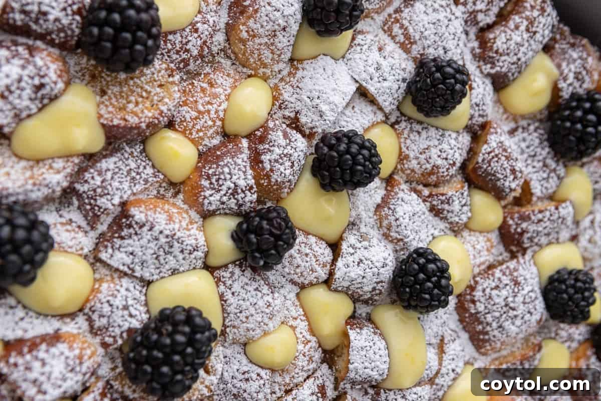 A beautiful Mother's Day brunch casserole made with pretzel French toast, topped with vibrant lemon curd, fresh blackberries, and a dusting of powdered sugar.