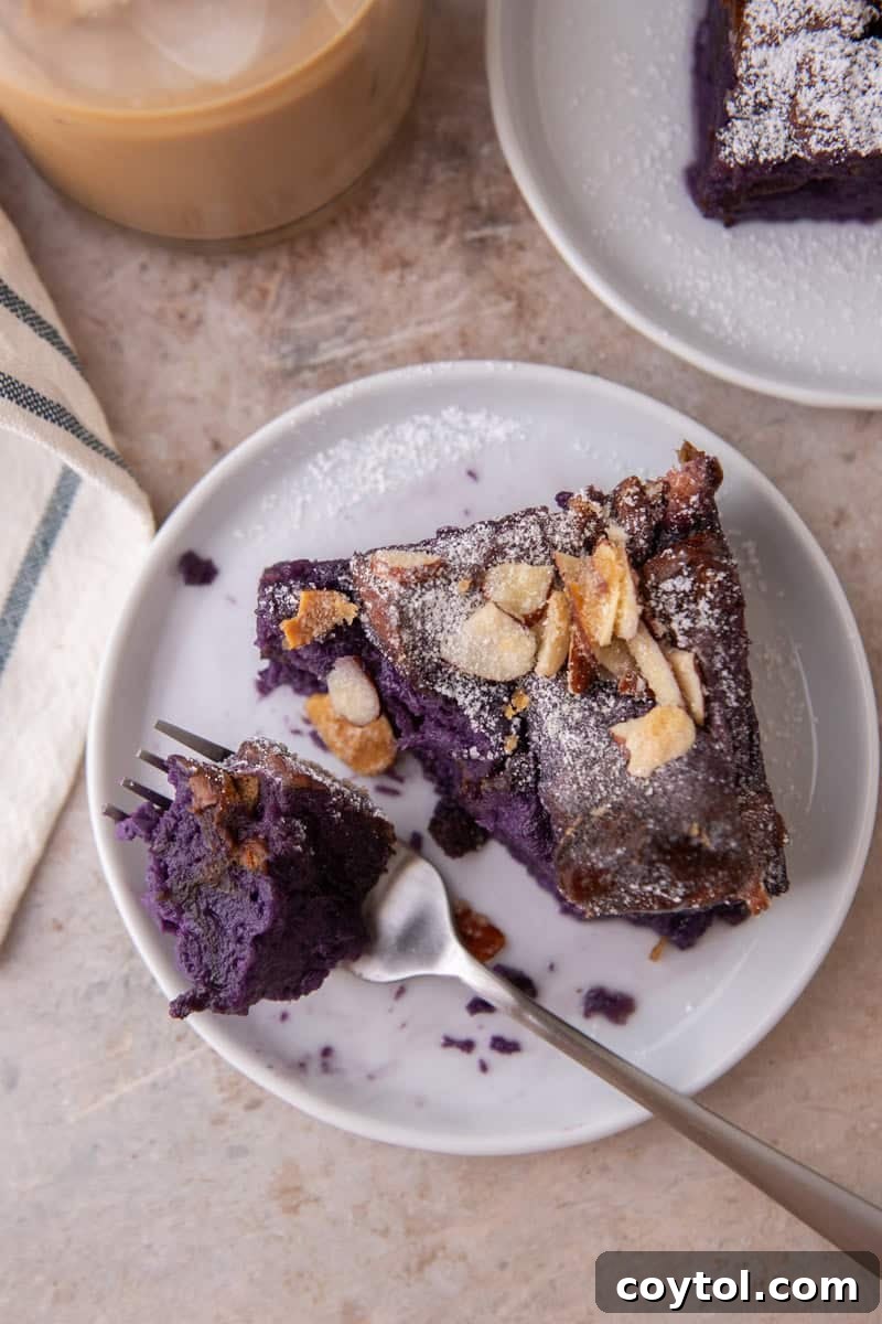 An overhead shot of a slice of ube French toast bake on a plate. A fork has taken a piece, showing the soft purple texture.