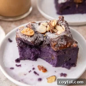A single serving of ube French toast bake on a white plate, showcasing its purple color and toasted almond topping.