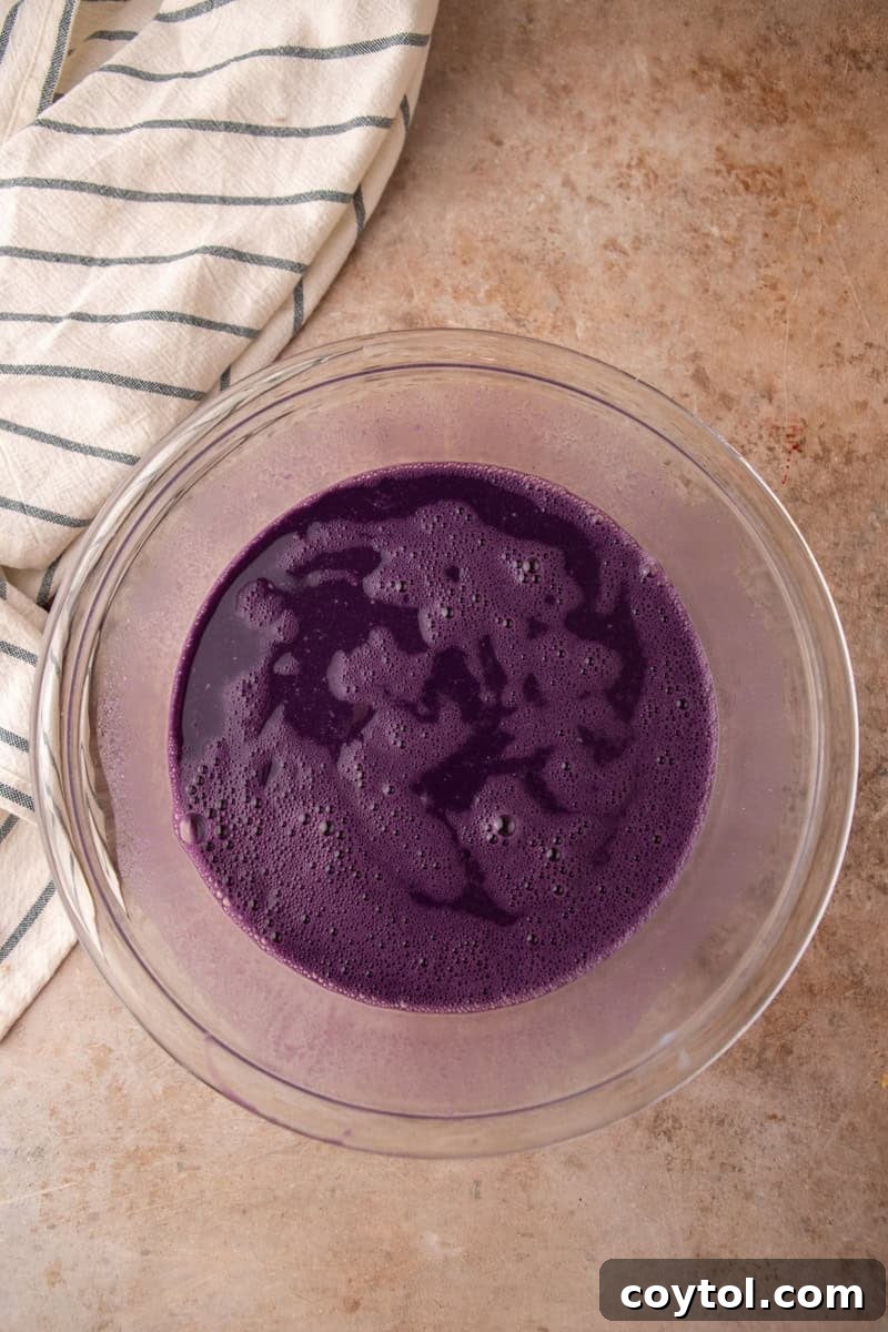 The ube custard is whisked until smooth, showing a vibrant, even purple color in the glass bowl.