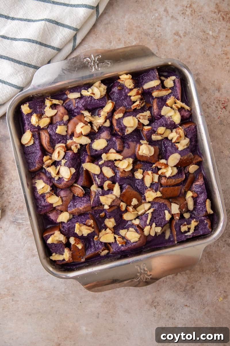The soaked ube French toast bake is now topped with a layer of buttered sliced almonds, ready for the oven.