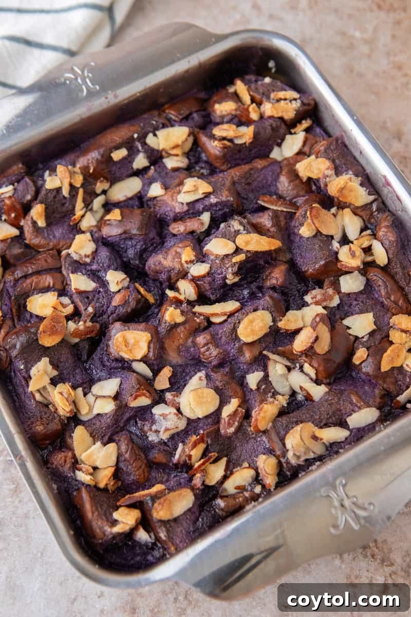 The freshly baked ube French toast casserole in its square pan, with a perfectly golden and crunchy toasted almond topping.