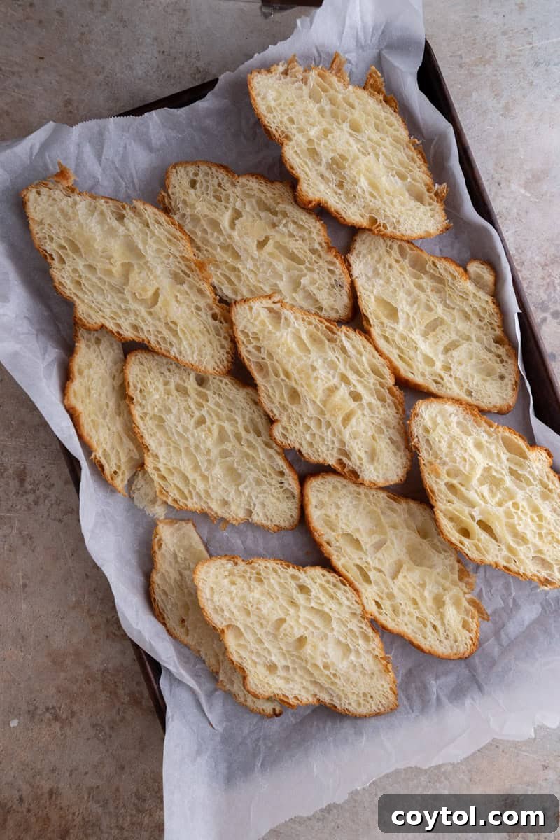 Day-old croissants sliced lengthwise and laid cut side down on a parchment-lined baking sheet