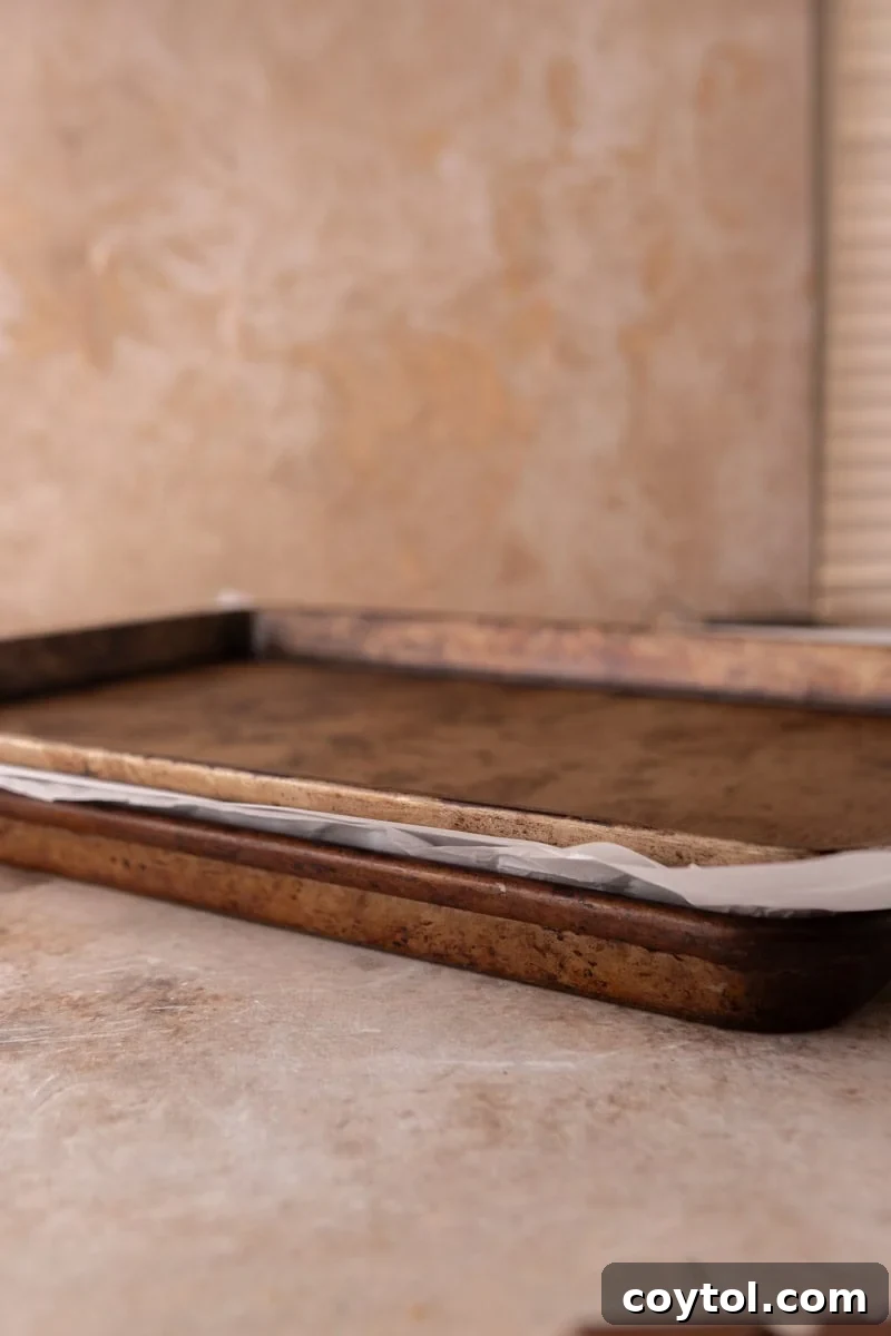 Two baking sheets stacked with parchment between to press croissants flat for croissant Christmas crack