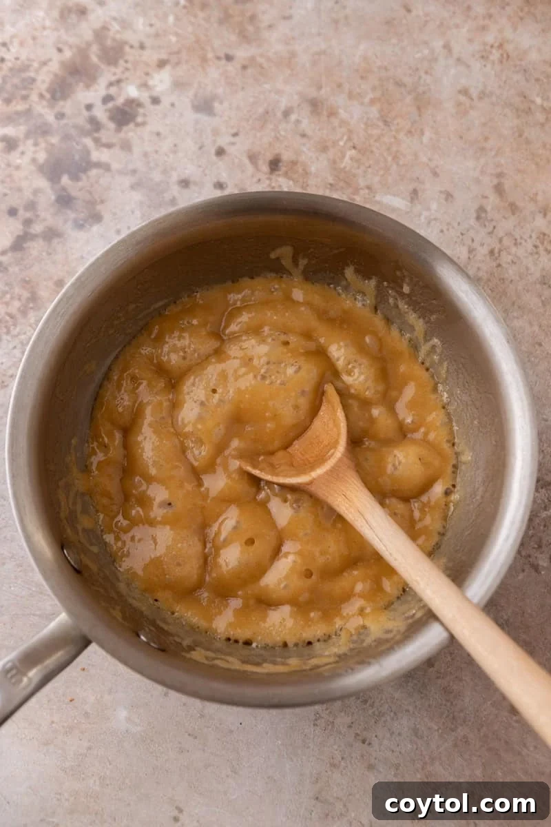 Brown sugar toffee bubbling in a saucepan with a wooden spoon, ready to pour over croissants