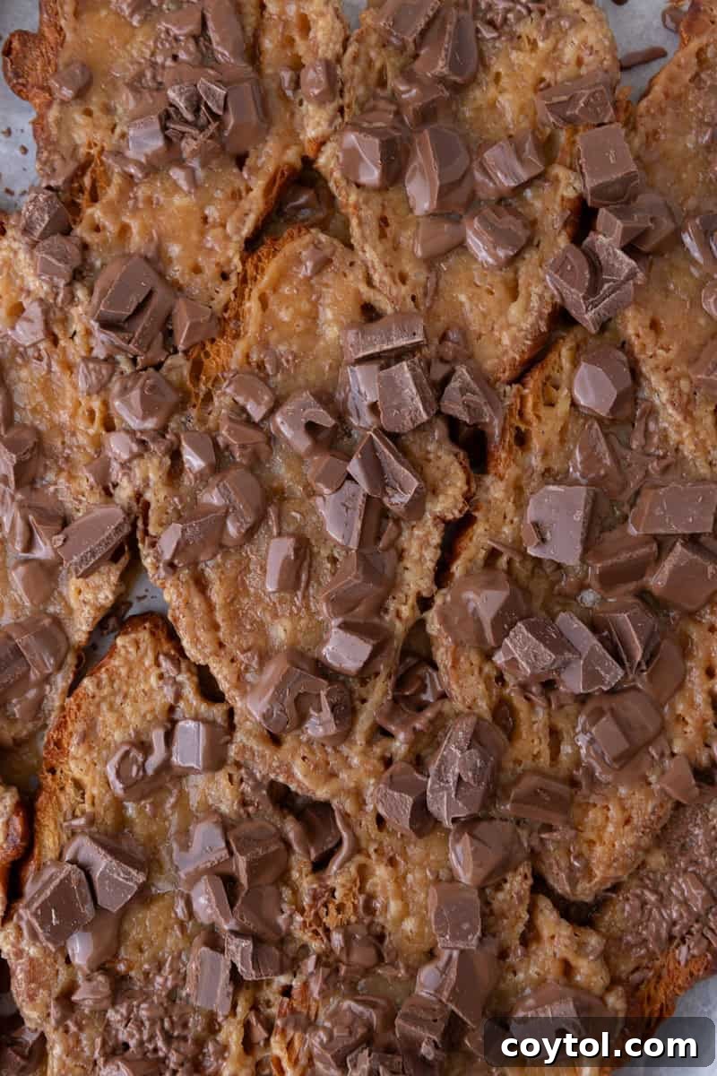 Chopped chocolate scattered over brown sugar toffee on pressed croissants for Christmas crack