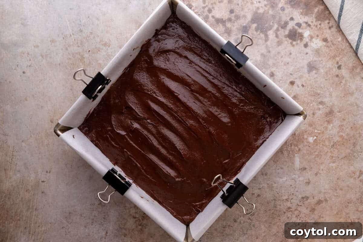 Melted chocolate spread over the peanut butter layer in a parchment lined pan