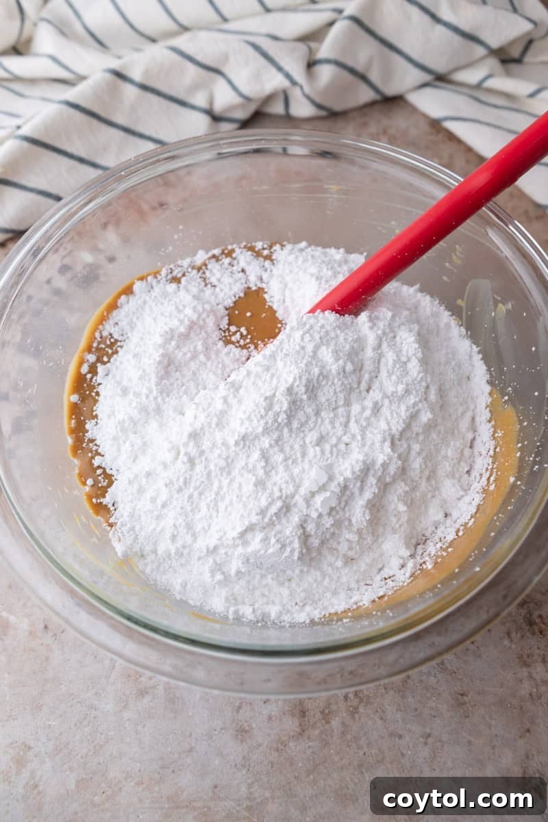 Powdered sugar added to the peanut butter mixture in a glass bowl
