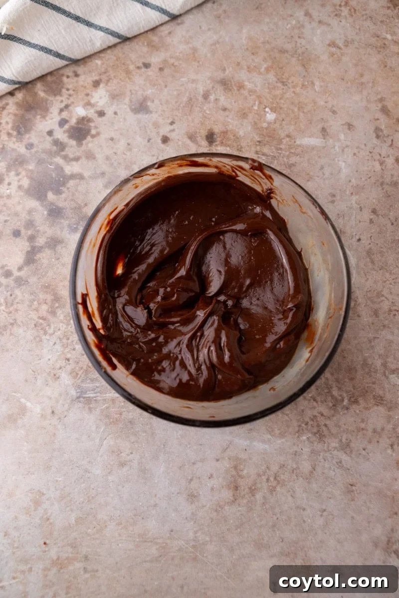 Smooth melted chocolate ganache in a glass bowl