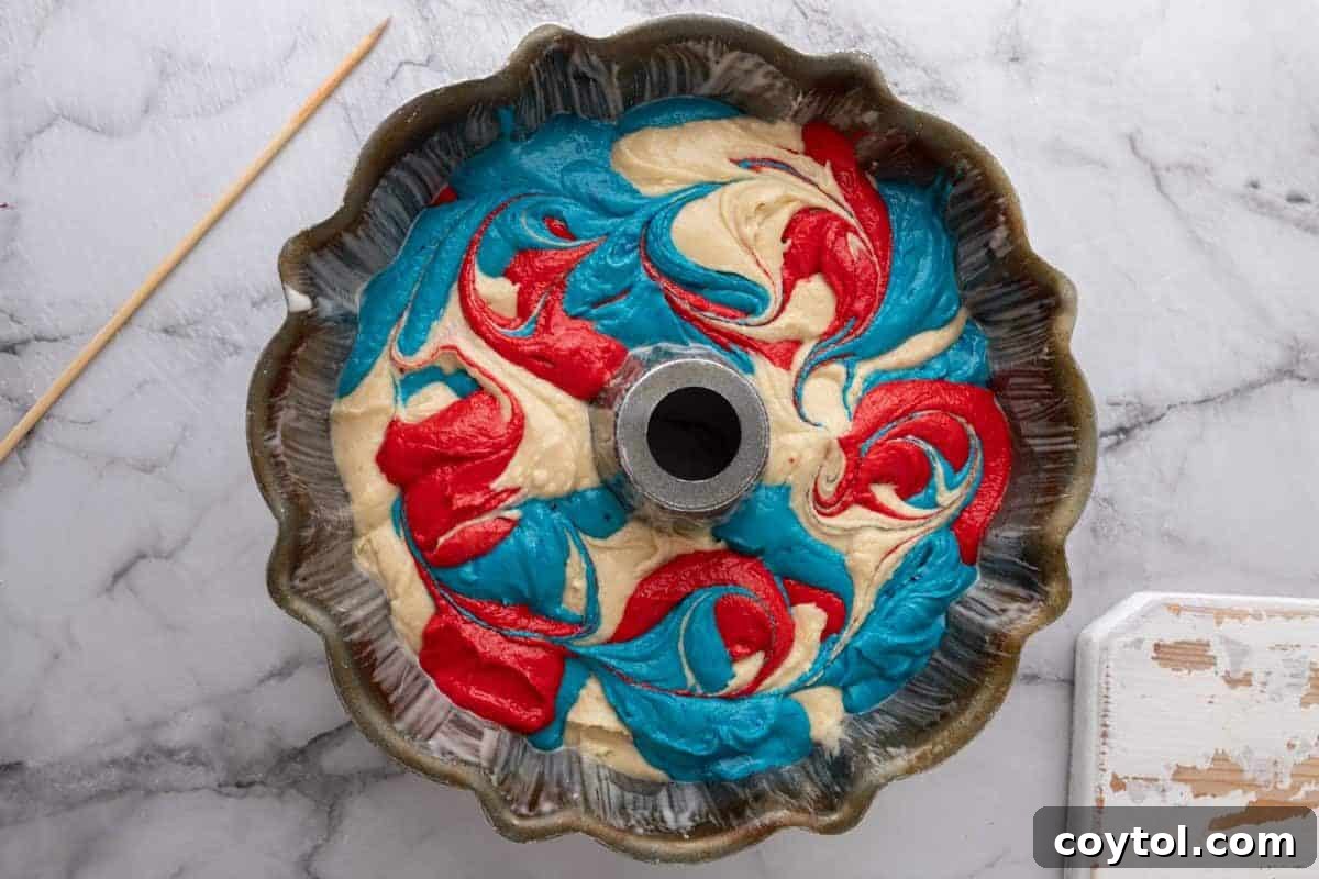 Red, white, and blue 4th of July bundt cake batter swirled in a bundt pan.