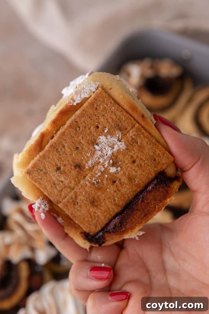 Hand holding a s'mores cinnamon roll showing the toasted graham cracker base on the bottom