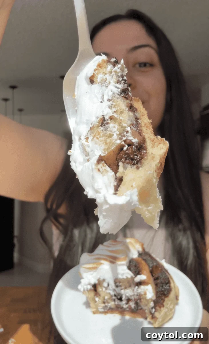 Forkful of a s'mores cinnamon roll with gooey chocolate and toasted meringue held over a plate