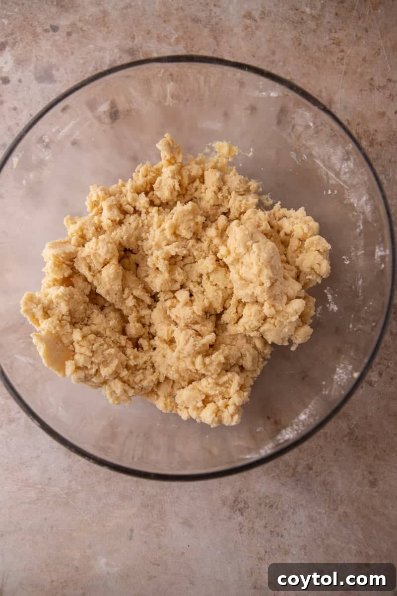Shortbread crumble dough mixed to a coarse shaggy texture in a glass bowl, ready to press into the pan
