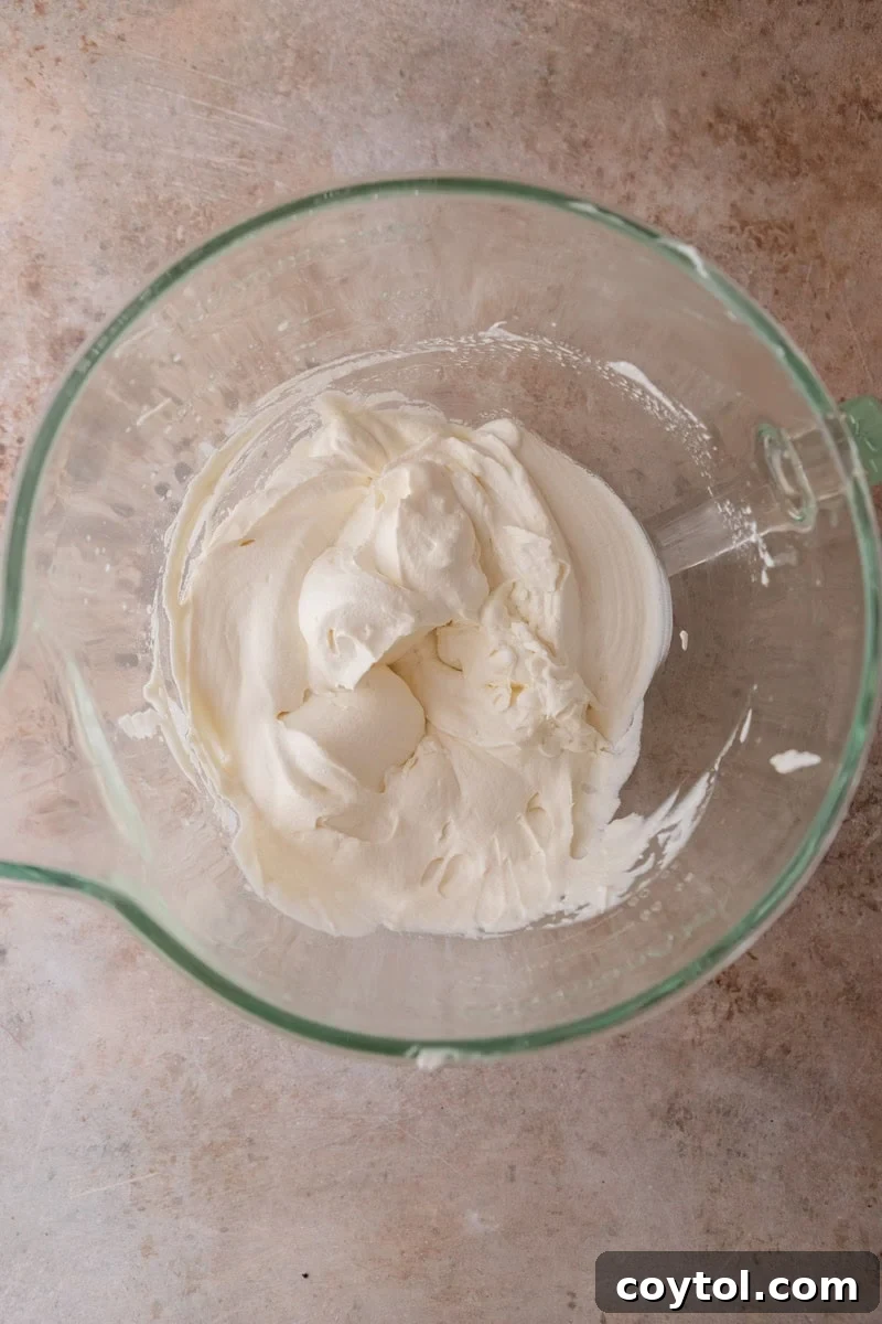 Heavy cream whipped to medium-stiff peaks in a glass measuring cup for the chocolate mousse