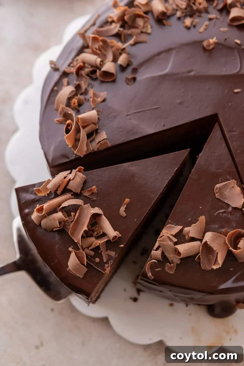 Overhead view of mousse cake topped with chocolate curls, with one slice being lifted out by a cake server