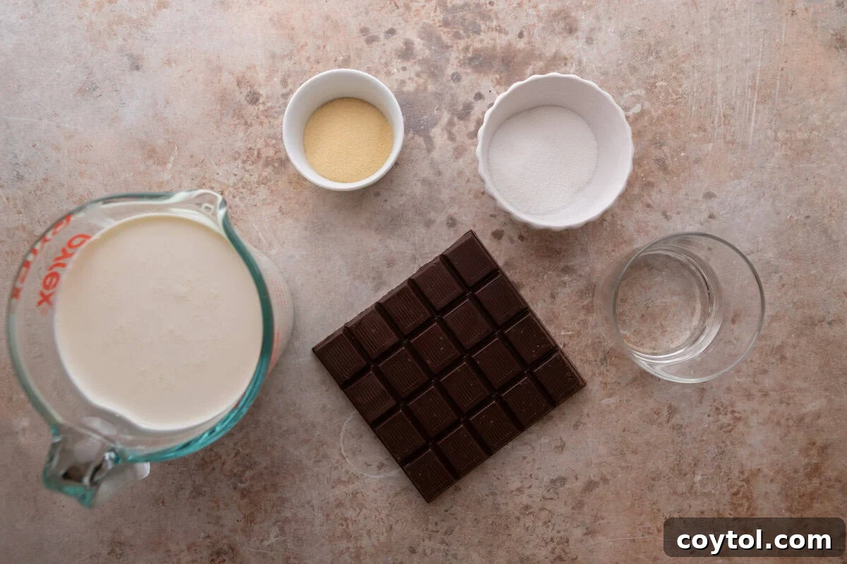Ingredients for the chocolate mousse layer including heavy cream in a measuring cup, a dark chocolate bar, powdered beef gelatin, sugar, and cold water