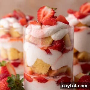 Strawberry shortcake cups showing distinct layers of cake, whipped cream, and sweet macerated strawberries.