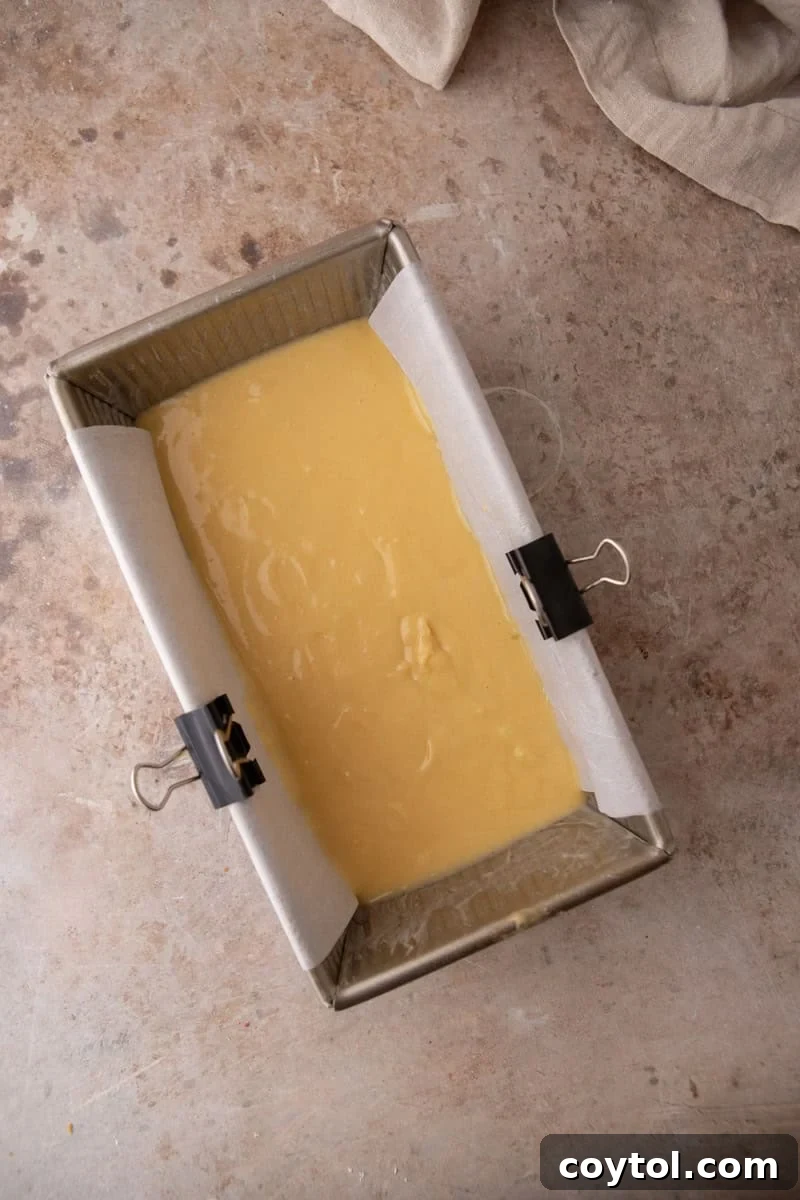Vanilla cake batter poured into a parchment lined loaf pan before baking.