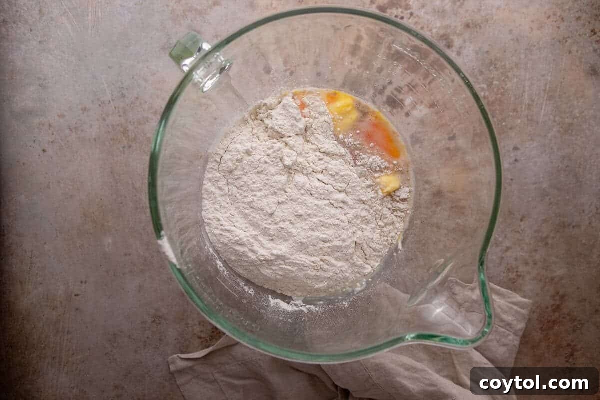 Flour, eggs, and melted butter in a glass mixing bowl for cinnamon roll dough