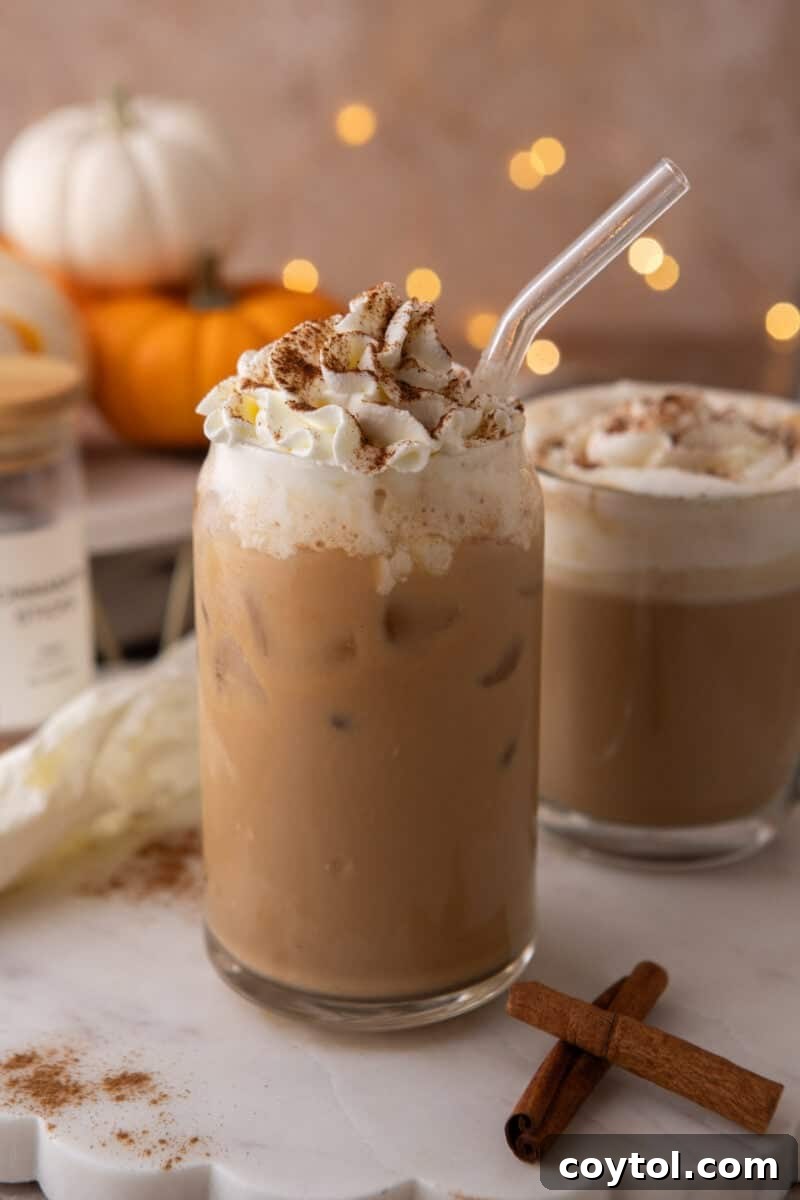 Iced pumpkin spice latte in a tall glass with cold milk poured over ice cubes.